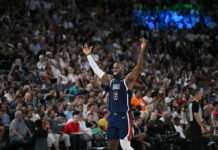 Basketball player in USA jersey raising arms crowds watching