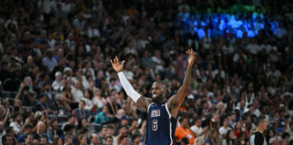 Basketball player in USA jersey raising arms crowds watching