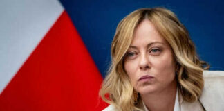 Person speaking at a conference with flag background