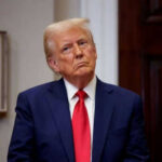Person in suit and red tie standing indoors