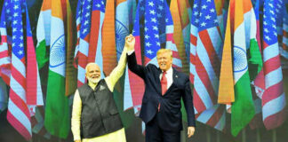 Two men holding hands on stage with flags behind