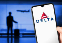 Person holding smartphone displaying Delta logo airport background