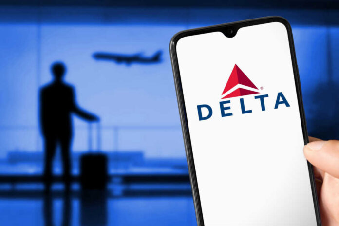 delta-airlines-logo-on-smarthphone2170782047jpg Person holding smartphone displaying Delta logo airport background