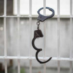 Open handcuff hanging on jail bars