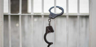 Open handcuff hanging on jail bars
