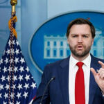 Man speaking at podium with US flag behind