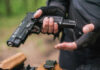Person holding a handgun with tactical gloves outdoors