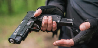 Person holding a handgun with tactical gloves outdoors