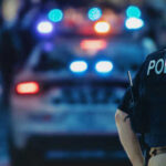 Police officer standing near patrol car with lights