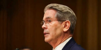 Man in suit speaking at a microphone indoors