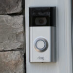 A smart doorbell mounted on a stone wall next to a door