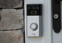 A smart doorbell mounted on a stone wall next to a door