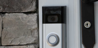 A smart doorbell mounted on a stone wall next to a door