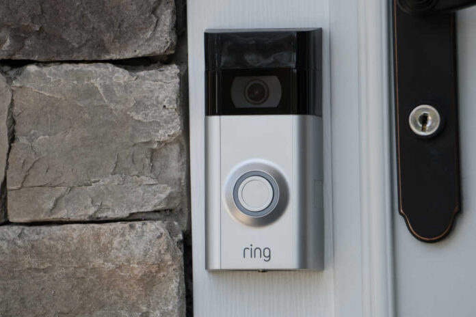A smart doorbell mounted on a stone wall next to a door