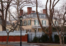 Historic mansion surrounded by bare trees and a fence