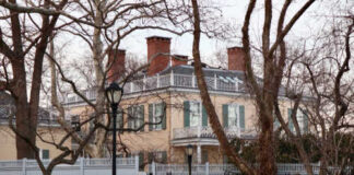 Historic mansion surrounded by bare trees and a fence