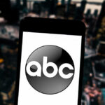A smartphone displaying the ABC logo against a blurred urban background