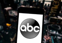 A smartphone displaying the ABC logo against a blurred urban background