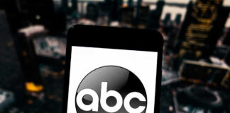 A smartphone displaying the ABC logo against a blurred urban background
