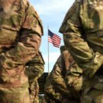 Soldiers standing in formation with an American flag in the background