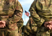 Soldiers standing in formation with an American flag in the background