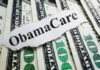 A piece of paper with 'ObamaCare' printed on it placed on top of U.S. dollar bills