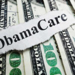 A piece of paper with 'ObamaCare' printed on it placed on top of U.S. dollar bills
