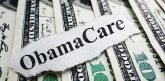 A piece of paper with 'ObamaCare' printed on it placed on top of U.S. dollar bills