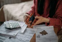 Person examining an empty wallet while surrounded by bills and a calculator