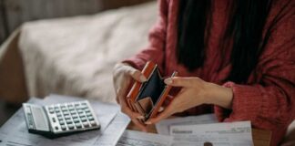 Person examining an empty wallet while surrounded by bills and a calculator