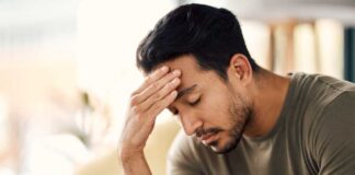 A man with a pained expression, holding his forehead in a moment of distress