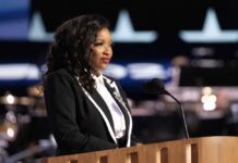 A woman in formal attire speaking at a podium with a microphone