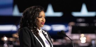 A woman in formal attire speaking at a podium with a microphone