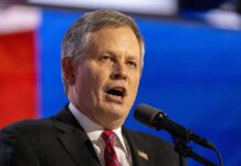 Man in formal attire speaking passionately into a microphone