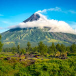 A majestic volcano surrounded by lush greenery and clouds