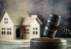 A wooden gavel in front of a model house