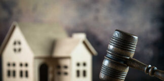 A wooden gavel in front of a model house