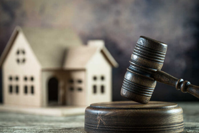 A wooden gavel in front of a model house