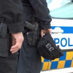 Two police officers standing near a patrol car