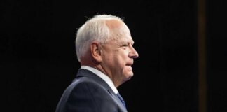 Elderly man in suit speaking on stage