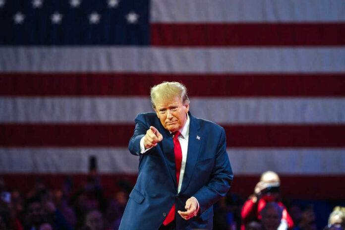 Man points in front of American flag backdrop.