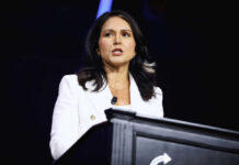 DNI Gabbard’s Silence: What Are They Hiding? Person speaking at a podium with microphone.