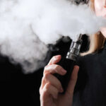 Shocking Vape Claim: Could It Spread MenB? Person vaping, exhaling thick vapor cloud.