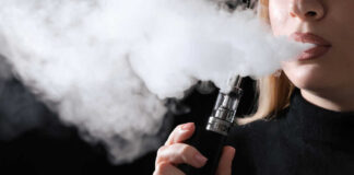 Person vaping, exhaling thick vapor cloud.