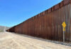 Tall border fence beside a dirt road desert