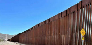 Tall border fence beside a dirt road desert