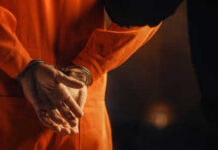 Person in orange jumpsuit with hands cuffed behind