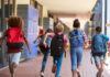 Children running with backpacks in a school corridor