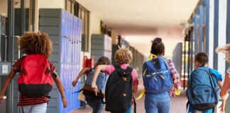 Children running with backpacks in a school corridor