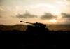 Silhouette of a tank against a sunset backdrop